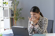 © amnaj - Asian businesswoman having flu and blowing her nose with tissue paper while working on a laptop at her home office