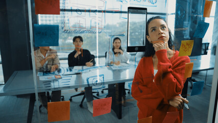 Wall Mural - Smart hispanic businesswoman present marketing strategy to diverse manager team. Beautiful successful leader thinking while looking at sticky notes on glass board. Grow to success. Manipulator.