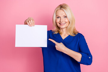 Poster - Photo portrait of pretty senior female hold point white paper sheet wear trendy blue outfit isolated on pink color background