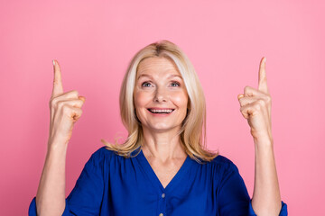 Wall Mural - Photo portrait of lovely pensioner lady point look up empty space dressed stylish blue garment isolated on pink color background