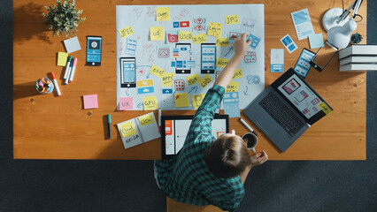 Top view of smart developer working on tablet and writing Ux Ui design for mobile phone interface at note. Manager design software program and sharing idea by using mind map. Top view. Convocation.