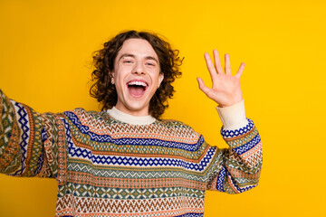 Poster - Photo of cheerful guy with wavy hairdo dressed ornament sweater making selfie waving palm say hello isolated on yellow color background