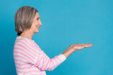 Sticker - Photo portrait of nice senior woman hold look empty space wear trendy striped outfit isolated on blue color background