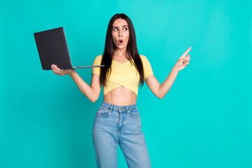 Wall Mural - Photo of pretty young woman hold laptop point finger empty space wear top isolated on teal color background