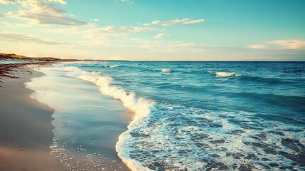 Canvas Print -   A stunning beach scene with crashing waves approaching the shoreline and a distant lighthouse illuminated on a bright sunny day