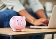 © Flashizzle/peopleimages.com - Piggy bank, person and laptop for saving in home, investment and banking website for finance plan. Money jar, container and cashback for income growth, insurance fund and future security on table