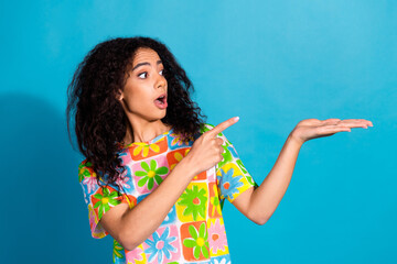 Poster - Photo of cheerful impressed lady dressed flower print t-shirt pointing finger holding arm empty space isolated blue color background