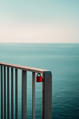 Canvas Print -   Red lock on railing, water below, blue sky above