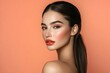 © Elmira - A beautiful woman with long dark brown hair styled in a low ponytail poses gracefully with a peach-colored background highlighting her features