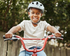 Black child, portrait and riding with bicycle or helmet for fun activity, hobby or outdoor exercise in nature. Young African, little boy or kid smile with bike for weekend of cycling in neighborhood