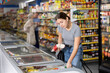 © JackF - Woman choosing frozen food in supermarket. Young woman purchasing goods in grocery store