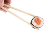 © mario - Holding piece of urumaki sushi roll with chopsticks isolated