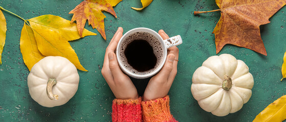 Poster - Female hands with cup of aromatic coffee, pumpkins and fallen leaves on color background