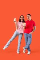 Wall Mural - Young couple with french fries on orange background