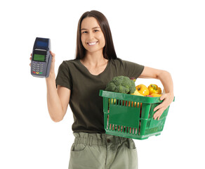 Wall Mural - Young woman with full shopping basket and payment terminal on white background