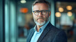© Siasart Stock - A mature man with glasses and a beard in a professional setting.