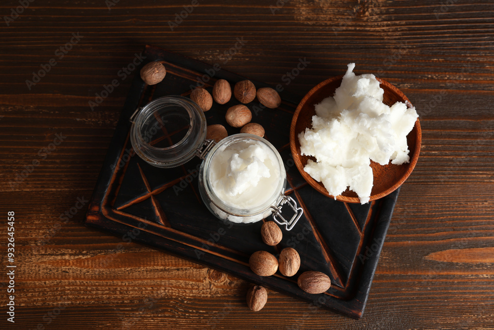 Cutting board with shea butter and nuts on wooden background