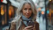 © Huy - mature businesswoman scrolling,smartphone going home from work beautiful older woman,gray hair walking down city street