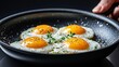 © Siripong - Fried eggs with vibrant yolks and fresh herbs, captured in a stylish skillet, perfect for breakfast and culinary presentations.