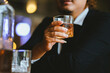 © Witoon - A young businessman holds a glass of whiskey, toasting with friends at an upscale bar. The scene captures the essence of luxury and celebration, with a focus on camaraderie and the nightlife atmospher