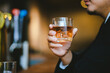 © Witoon - A young businessman holds a glass of whiskey, toasting with friends at an upscale bar. The scene captures the essence of luxury and celebration, with a focus on camaraderie and the nightlife atmospher
