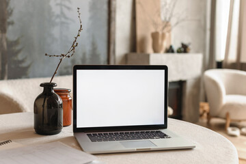 A home office concept with a blank laptop screen on a table in a modern living room in Scandinavian style.