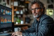 © Nata - A small business owner sitting at a desk, intently looking at graphs on a computer screen. Generative AI