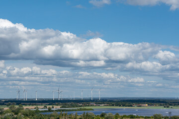 A large group of wind turbines are visible in the distance, with a clear blue sky in the background