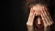 © Chaiwit - A young woman expresses distress, holding her head with pained expression. dark background emphasizes her emotional struggle.