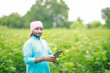 happy young Indian farmer using smart phone