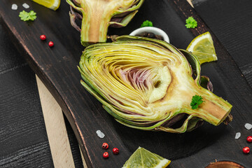 Fresh green artichokes cooking on wooden background. Traditional seasonal ingredients