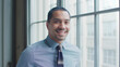 © Monkey Business - Head And Shoulders Portrait Of Smiling Young Businessman Standing By Window In Office