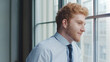© Monkey Business - Head And Shoulders Portrait Of Smiling Young Businessman Looking Out Of Window In Office
