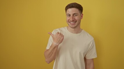 Sticker - Young hispanic man standing and pointing to the side with a happy, smiling, open mouth and thumbs up over an isolated yellow background