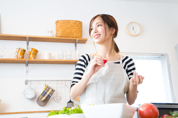 Wall Mural - キッチンで料理を作る若い女性