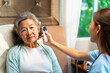 © CandyRetriever  - Asian woman doctor examine patient use infrared thermometer measured temperature in senior woman ear in bedroom. Nurse visit and checking elderly patient health at home. Home medical therapy concept.