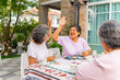 © CandyRetriever  - Group of Happy Asian senior mature women relax and enjoy indoor lifestyle meeting party together at home. Elderly retired woman friends having fun playing card together at home garden in summer day.
