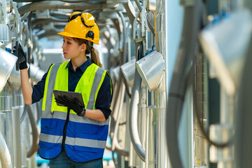 Wall Mural - Professional Asian woman engineer in safety uniform working on digital tablet at outdoor construction site rooftop. Industrial technician worker maintenance checking building exterior air HVAC systems