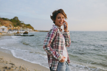 Wall Mural - Young fun woman wear shirt casual clothes talk speak on mobile cell phone conducting pleasant conversation rest on sea ocean sand shore beach outdoor seaside in summer day free time Lifestyle concept