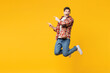 © ViDi Studio - Full body young happy man he wears red checkered shirt casual clothes jump high point index finger aside on area mock up isolated on plain yellow orange background studio portrait. Lifestyle concept.