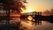 © Putt_Sanplee - A footbridge spanning a tranquil river, with the sun rising in the distance and reflecting off the water's surface.