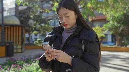 Sticker - A young asian woman checks her smartphone in a sunny urban park.