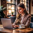 © ArtyKris99 - a beautiful young woman sitting at a table with a cup of coffee in a business class room working on a laptop
