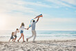 © Frank Coop/peopleimages.com - Family, flying kite and holding hands on beach together for holiday, travel or vacation in summer. Energy, love or running with mother, father and kids on sand at coast by ocean or sea for bonding