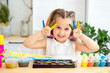 © Any Grant - a small child, a girl with painted hands in paints, learns to draw by playing, a girl plays around and has fun in a drawing lesson at an art school