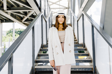 Beautiful brunette businesswoman wearing suit and white hat, walking on the street.