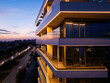 © sandsun - Aerial drone shot of a modern building facade illuminated by sleek LED lighting at dusk, capturing the contrast between the urban night skyline and contemporary architecture