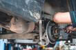 © chartphoto - A mechanic working on a car's brake system, focusing on the rear wheel components in an auto repair workshop.