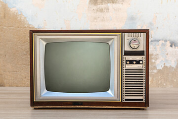 Wall Mural - Retro old tv with blank screen on wooden table with old concrete wall background, front view