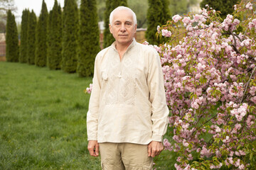 Senior man with gray hair in green nature background